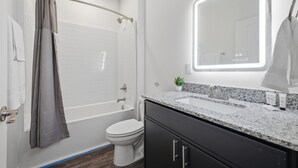 Een moderne badkamer met een douche, toilet en wastafel met spiegel.