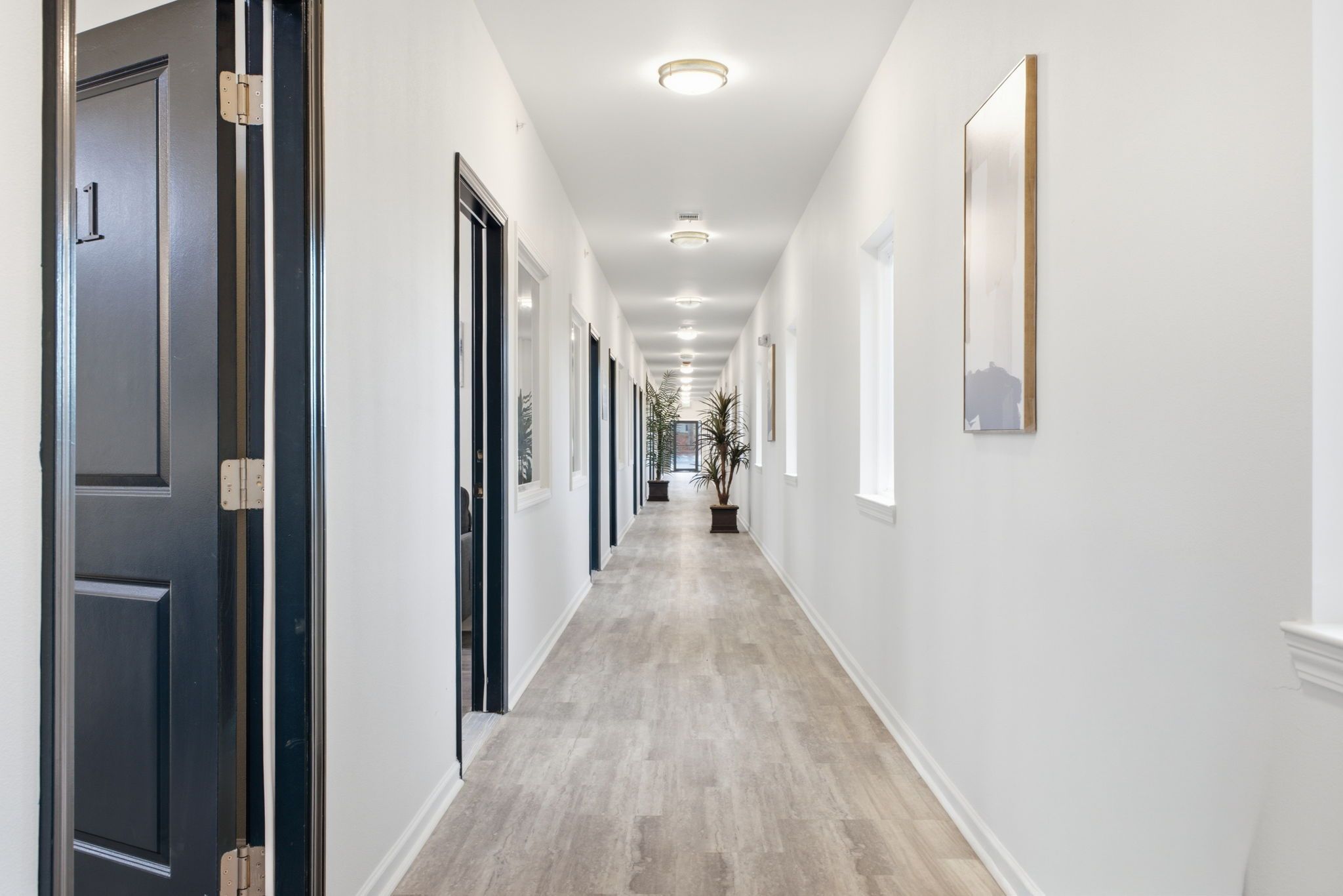 A hallway with a light-colored floor, white walls, and doors on both sides.