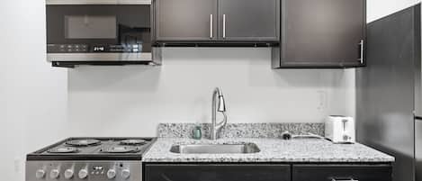 A kitchen with a stove, oven, sink, and dark cabinets.