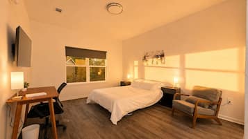 Ein Hotelzimmer mit Bett, Schreibtisch, Stuhl und einem Fenster mit Blick.