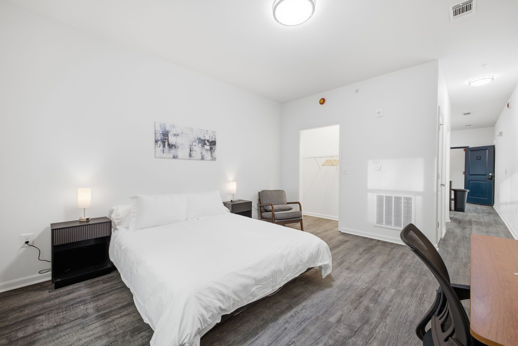 Ein Hotelzimmer mit Bett, Nachttisch, Stuhl und Schreibtisch.