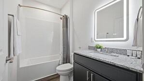 Moderni kylpyhuone, jossa on kylpyamme, wc ja pesuallas.
