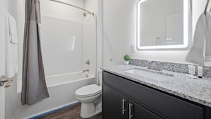 A modern bathroom with a shower, toilet, and sink.