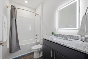 A modern bathroom with a shower, toilet, and sink.