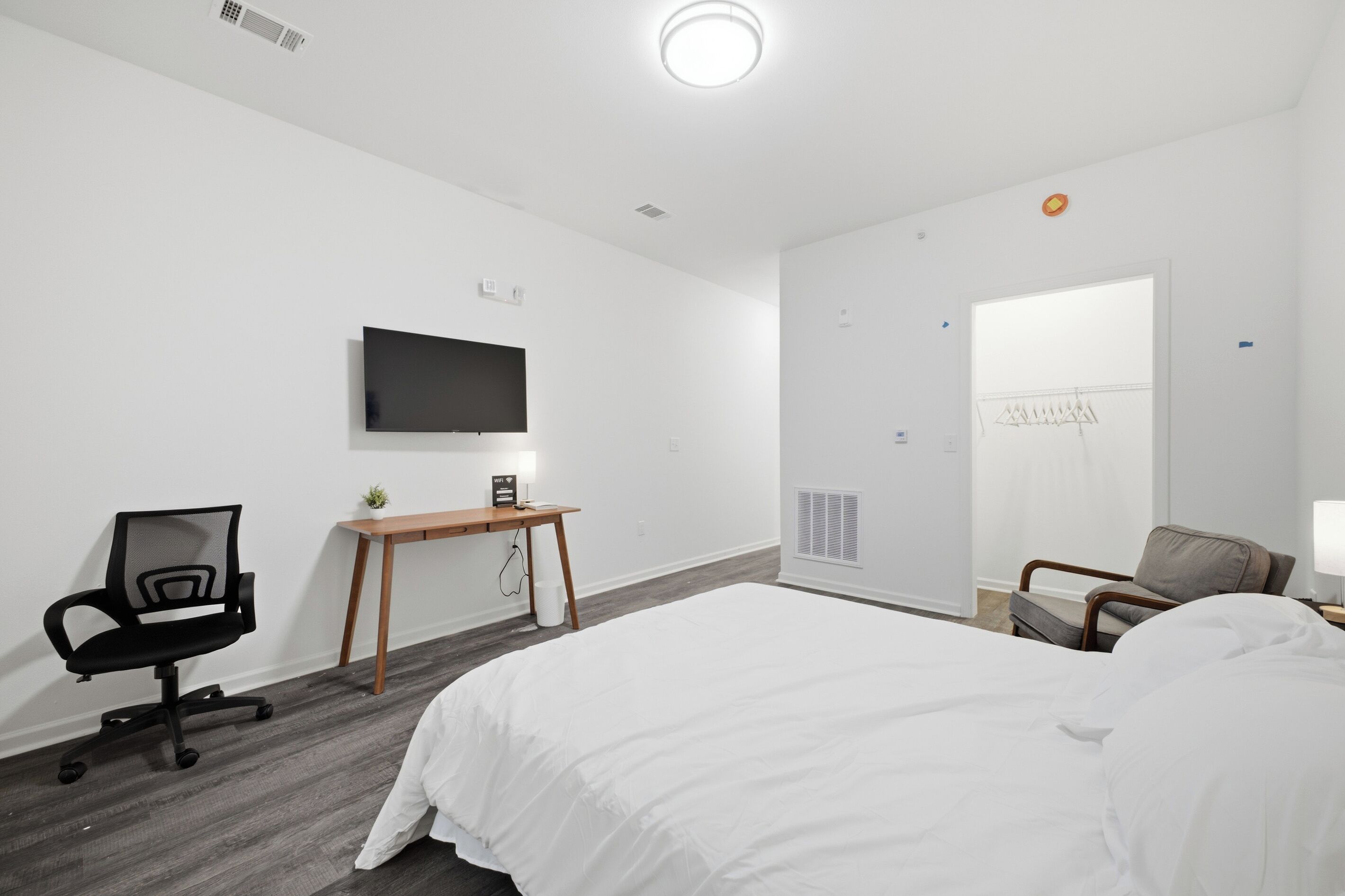 A hotel room with a bed, a desk, a chair, a TV, and a wardrobe.