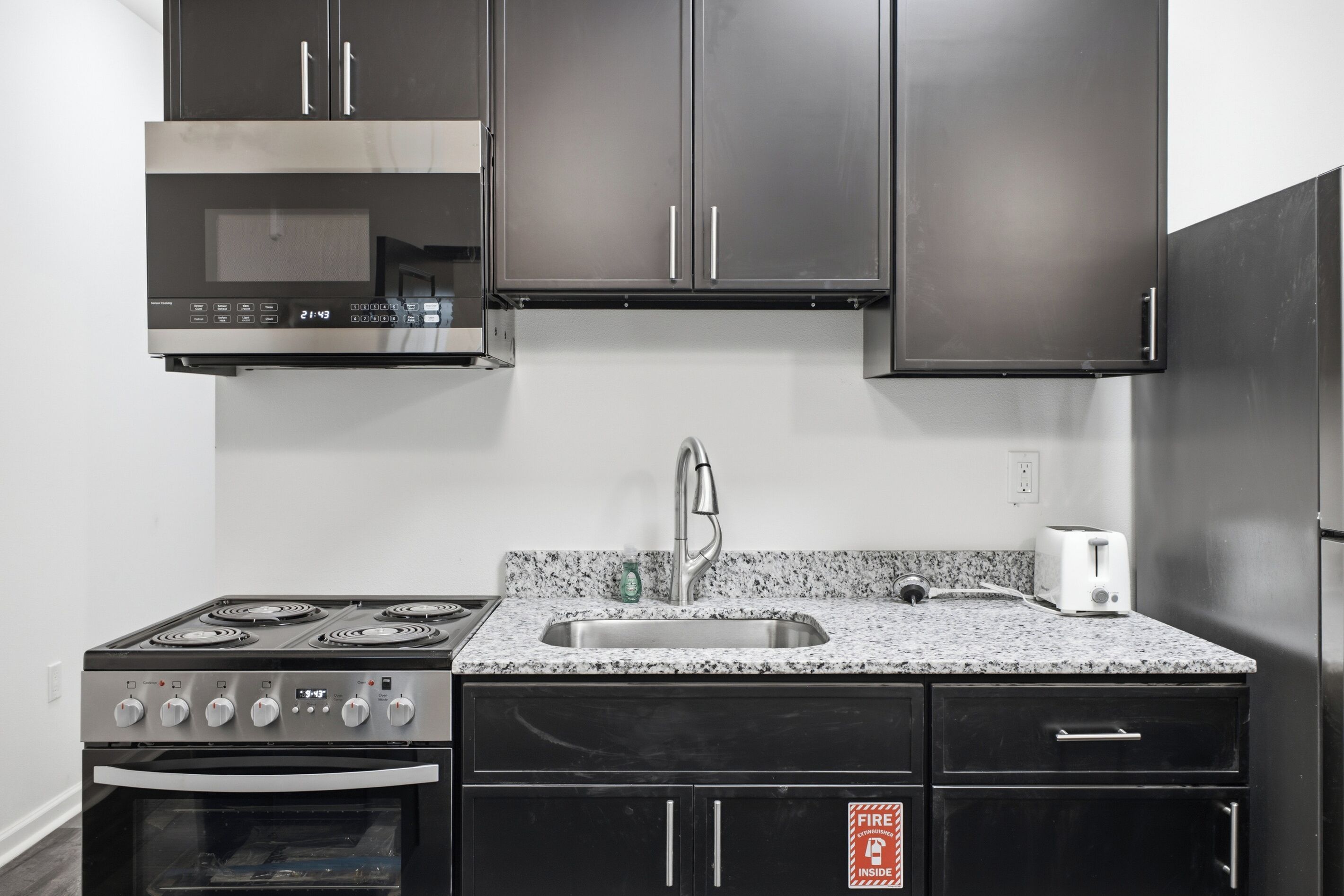 A kitchen with a stainless steel range, a built-in oven, a granite countertop, a stainless steel sink, and a white toaster.