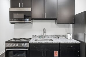 A kitchen with a stainless steel range, a built-in oven, a granite countertop, a stainless steel sink, and a white toaster.