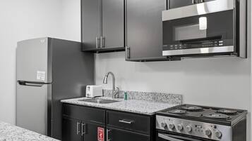 A modern kitchen with a refrigerator, microwave, stove, and sink.