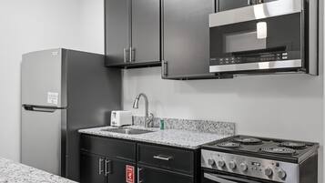 A kitchen with a stainless steel refrigerator, microwave, stove, and sink.