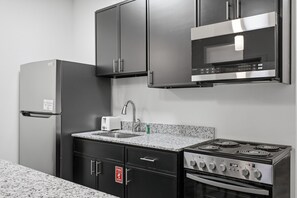 A kitchen with a stainless steel refrigerator, microwave, stove, and sink.