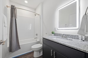 A modern bathroom with a shower, toilet, and sink.