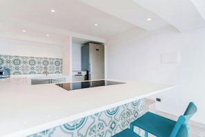 Een moderne keuken met een centraal kookeiland, roestvrijstalen apparatuur en een decoratieve achterwand.