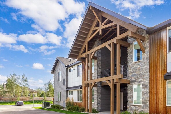 A modern two-story house with a stone facade, wooden beams, and large windows.