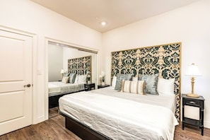 A bedroom with a large bed, a mirror, a nightstand, and a lamp. - Elegant 1BD Condo | NOLA Walkable Escape (New Orleans)