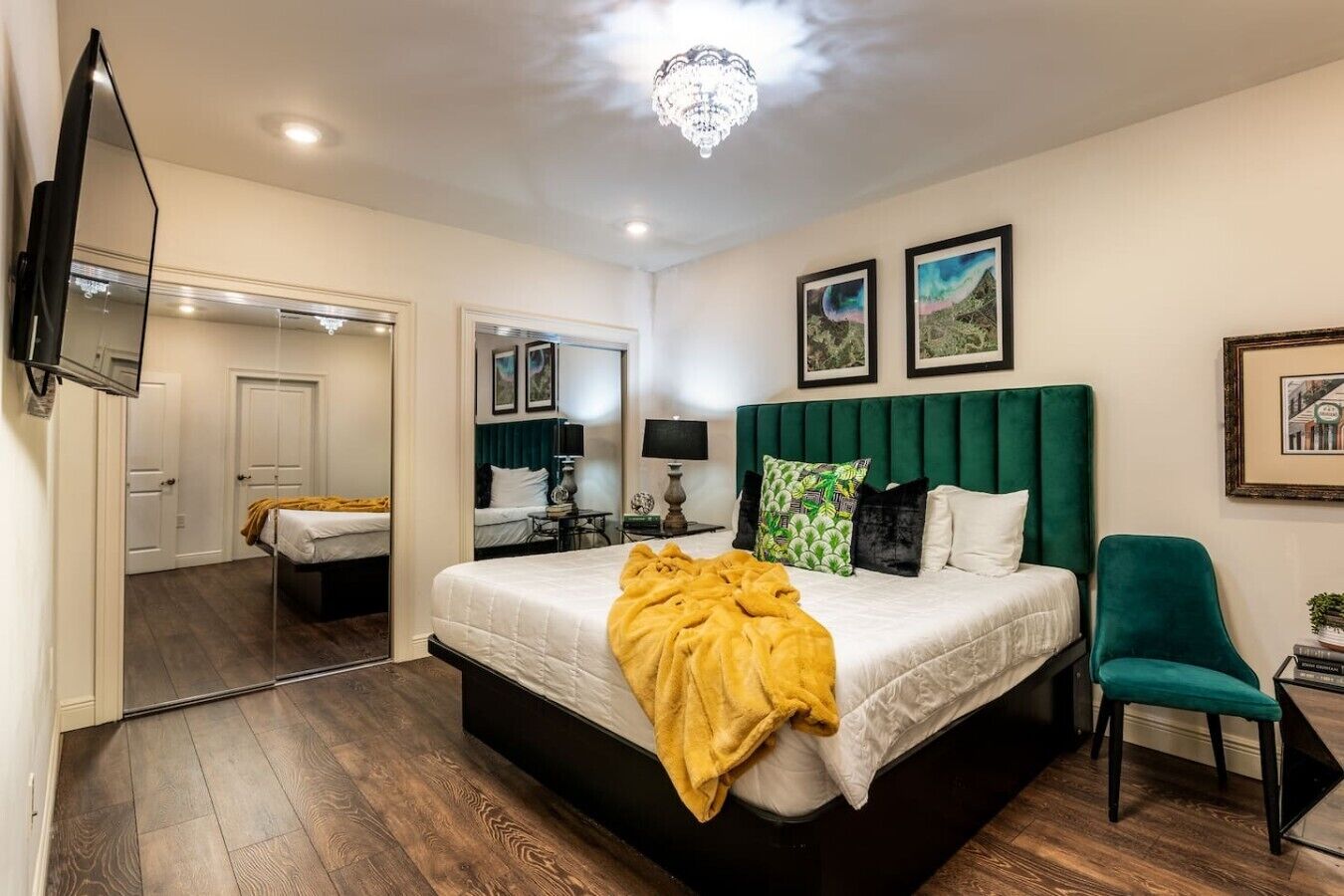 A bedroom with a bed, a chair, a TV, and a mirror.