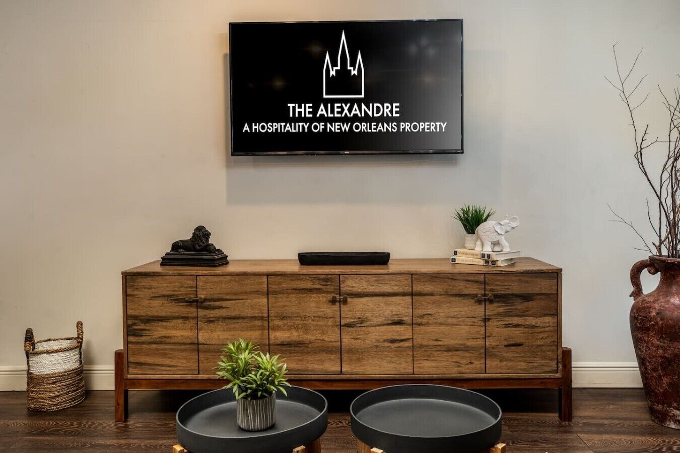 Een houten console met een televisie erboven waarop staat: 'THE ALEXANDRE A HOSPITALITY OF NEW ORLEANS PROPERTY'.