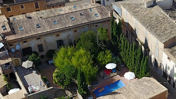 An aerial view of a courtyard with a swimming pool, surrounded by buildings with terracotta roofs and greenery. - Room 'Suite Summer' with Shared Pool, Wi-Fi and Air Conditioning (Alaró)