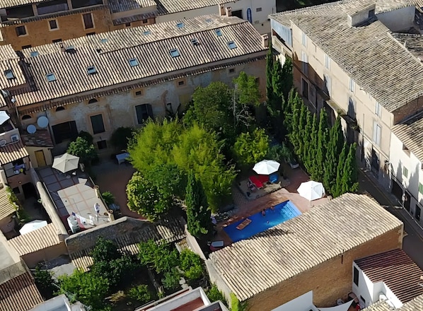 An aerial view of a courtyard with a swimming pool, surrounded by buildings with terracotta roofs and greenery. - Room 'Suite Summer' with Shared Pool, Wi-Fi and Air Conditioning (Alaró)