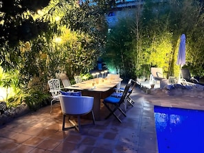 An outdoor dining area with a table and chairs, surrounded by lush greenery and a pool. - Room 'Suite Summer' with Shared Pool, Wi-Fi and Air Conditioning (Alaró)
