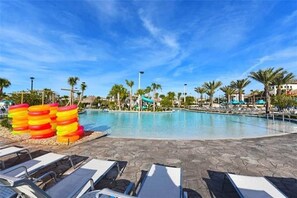 Une piscine avec des chaises longues et des palmiers.