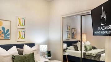 A hotel room with a bed, bedside tables, a mirror, and artwork on the walls.
