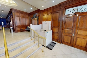 Een hotel ontvangsthal met een trap, houten lambrisering en een receptie.