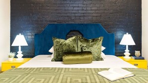 A bed with a blue headboard, two pillows, a green throw, and a book on the bedside table. - 2BD/2BA in NOLA’s Best Walkable Neighborhood (New Orleans)