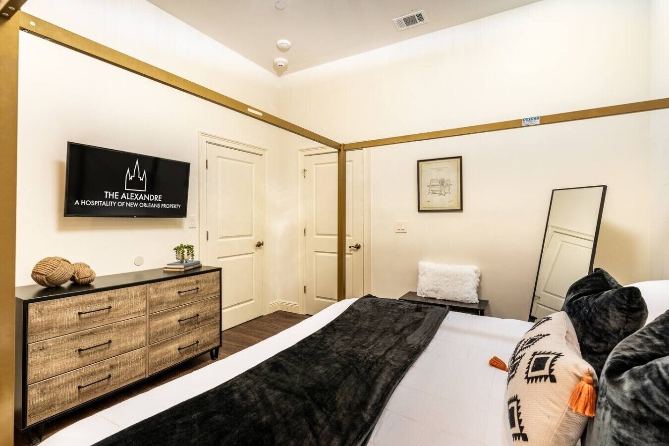 A hotel room with a bed, a dresser, a television, and a framed picture on the wall.