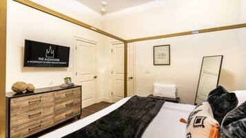 A hotel room with a bed, a dresser, a television, and a framed picture on the wall.