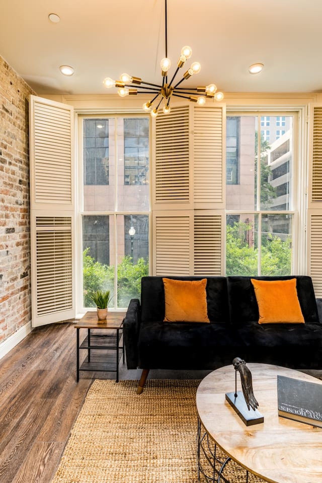 A modern living room with a black sofa, a round coffee table, and a hanging light fixture.