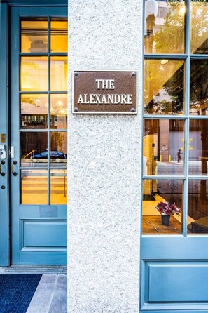 A building entrance with a sign reading 'THE ALEXANDRE' and a blue door. - Group-Friendly NOLA Stay | Steps to French Quarter (New Orleans)