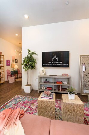 A modern living room with a flat-screen TV, a potted plant, and a colorful rug. - Group-Friendly NOLA Stay | Steps to French Quarter (New Orleans)