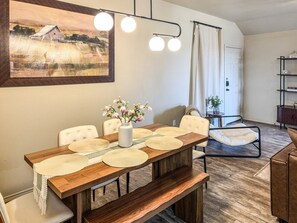 A dining area with a wooden table, white chairs, and a vase with flowers. - Pontiac Lubbock - 3-Bedroom Home in Lubbock, Texas (Lubbock)