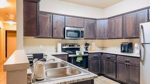A modern kitchen with dark wood cabinets, stainless steel appliances, and a granite countertop. - Pontiac Lubbock - 3-Bedroom Home in Lubbock, Texas (Lubbock)