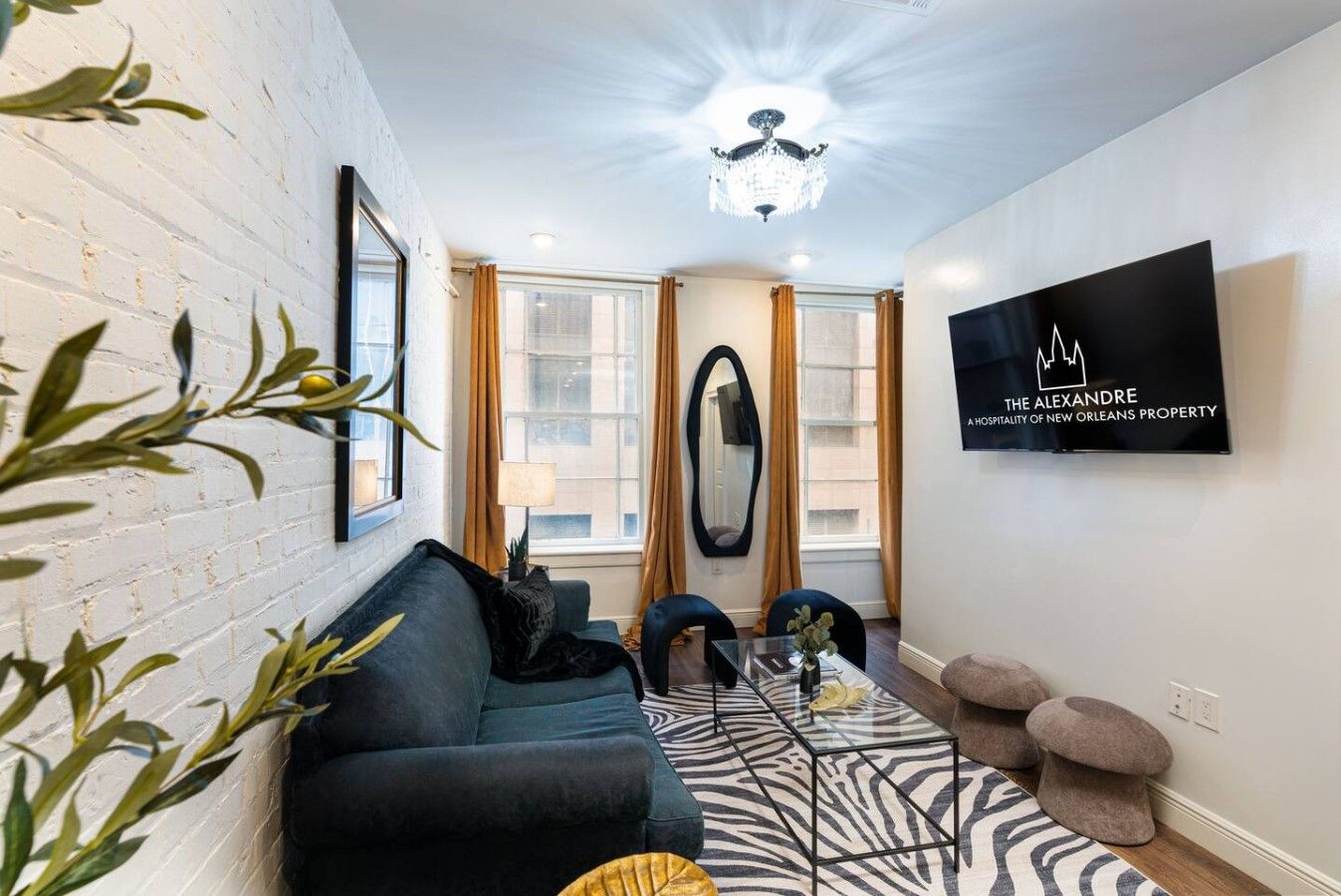 Un salon moderne avec un canapé noir, une table basse en verre et un tapis à motifs zébrés.