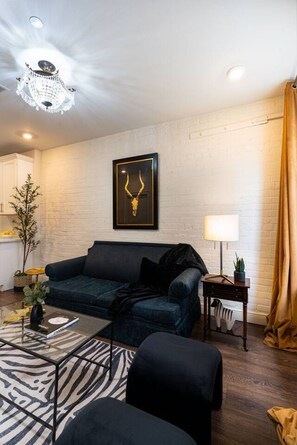 A modern living room with a dark blue sofa, a zebra-patterned rug, and a chandelier. - Prime NOLA Stay | 2BD Near Bourbon + Canal (New Orleans)