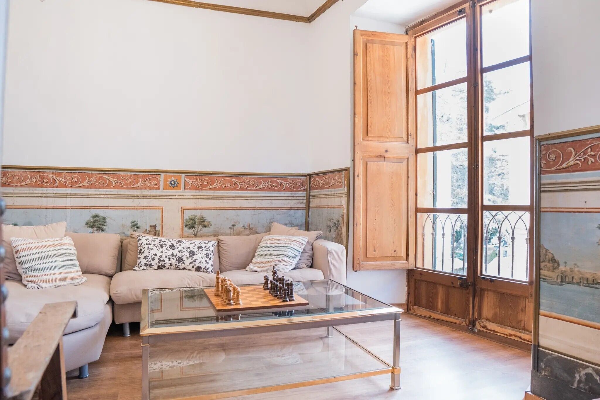 A living room with a sofa set, a glass coffee table, and a chessboard.