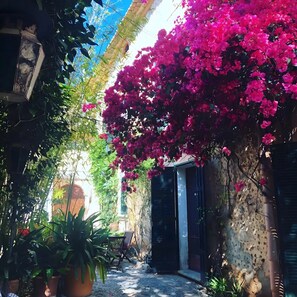 A courtyard with a pergola covered in pink bougainvillea, potted plants, and a seating area. - Vintage Suites Room with Lounge, Shared Pool, Wi-Fi and Air Conditioning (Alaró)