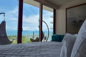 Une chambre avec un lit, une vue sur la mer et une grande fenêtre.