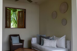 A living room with a sofa, a chair, a coffee table, and a window with shutters. - 3 BR · 2 Pools · Jungle Club · Beach Club (La Cruz de Huanacaxtle)