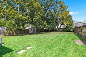 A backyard with a lawn, a small shed, and a wooden fence.