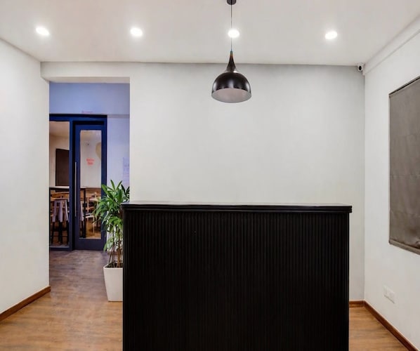 A room with a black partition, recessed ceiling lights, a potted plant, and a door leading to another room.
