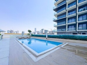 Ein Pool auf dem Dach mit Blick auf eine Stadtlandschaft im Hintergrund.