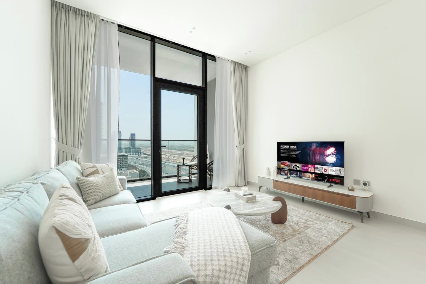Ein modernes Wohnzimmer mit einer Couch, einem Couchtisch und einem Flachbildfernseher, der eine Fernsehsendung zeigt.
