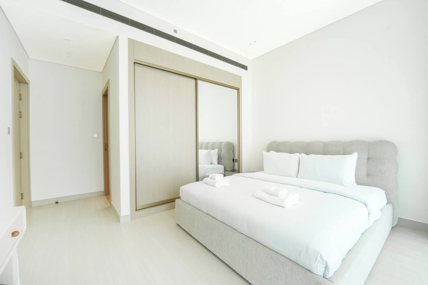 Un dormitorio moderno con una cama grande, un armario y un espejo.