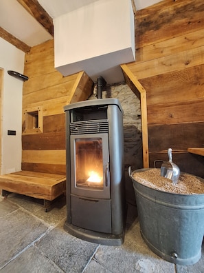 Ein Holzofen mit einem Metall-Holzpellet-Eimer daneben.
