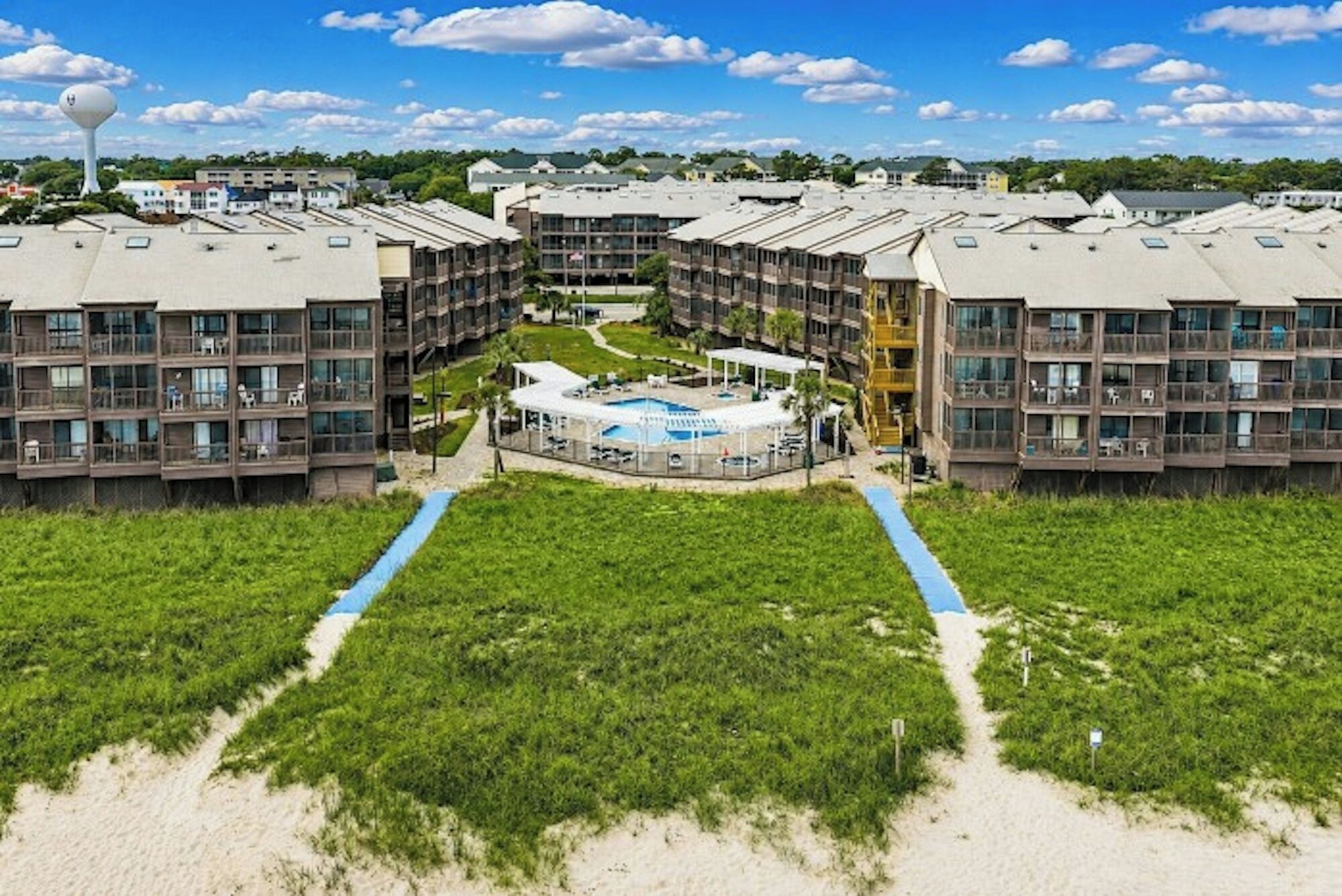 Een hotel met meerdere verdiepingen, een centrale binnenplaats, een buitenzwembad en toegang tot het strand.