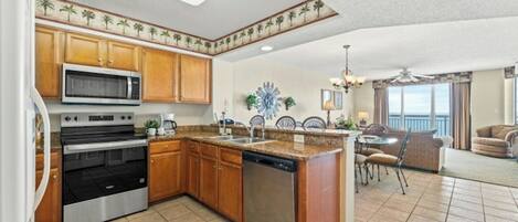 A kitchen with a central island, built-in microwave, double ovens, and wooden cabinets.