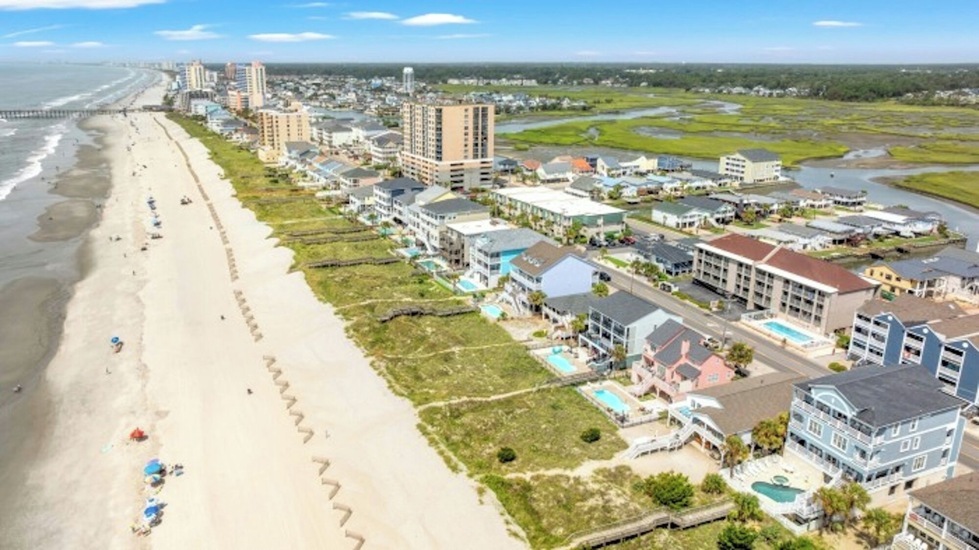 Ein Küstenhotel mit mehreren Gebäuden, einem Strand und einem Fluss.