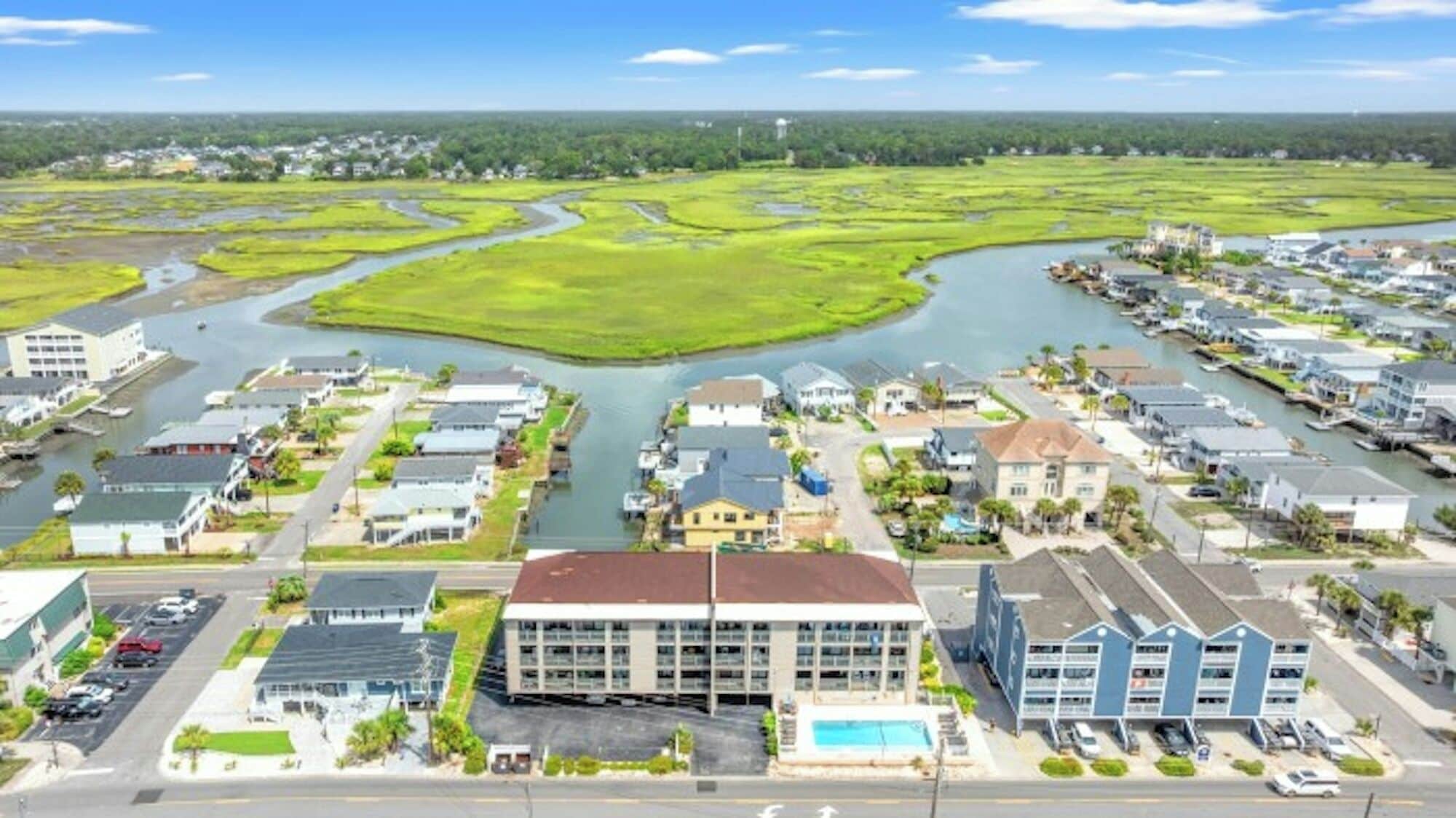 Une ville côtière traversée par une rivière, avec des immeubles d’habitation et un grand hôtel doté d’une piscine.
